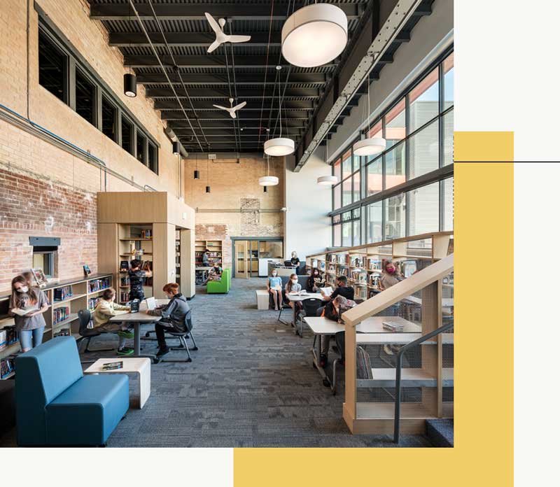 Student library featuring wall to ceiling windows, tables, and bookshelves