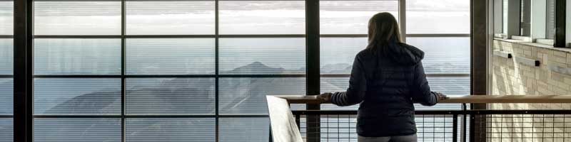 Woman standing at the railing of the second floor overlooking the lobby of the Pikes Peak Summit Visitors Center