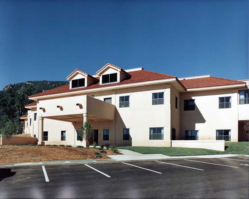 Exterior view of the Penrose Hospital Namaste entrance, featuring a distinctive curved canopy, large glass windows, and a welcoming entryway. The design emphasizes a calming and inviting atmosphere for patients and visitors.