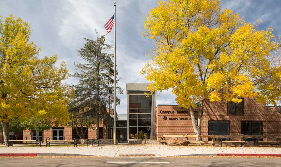 Exterior view of Bear Creek Elementary School, showcasing modern architectural design with large glass windows, clean lines, and a spacious outdoor area surrounded by lush greenery under a clear blue sky.