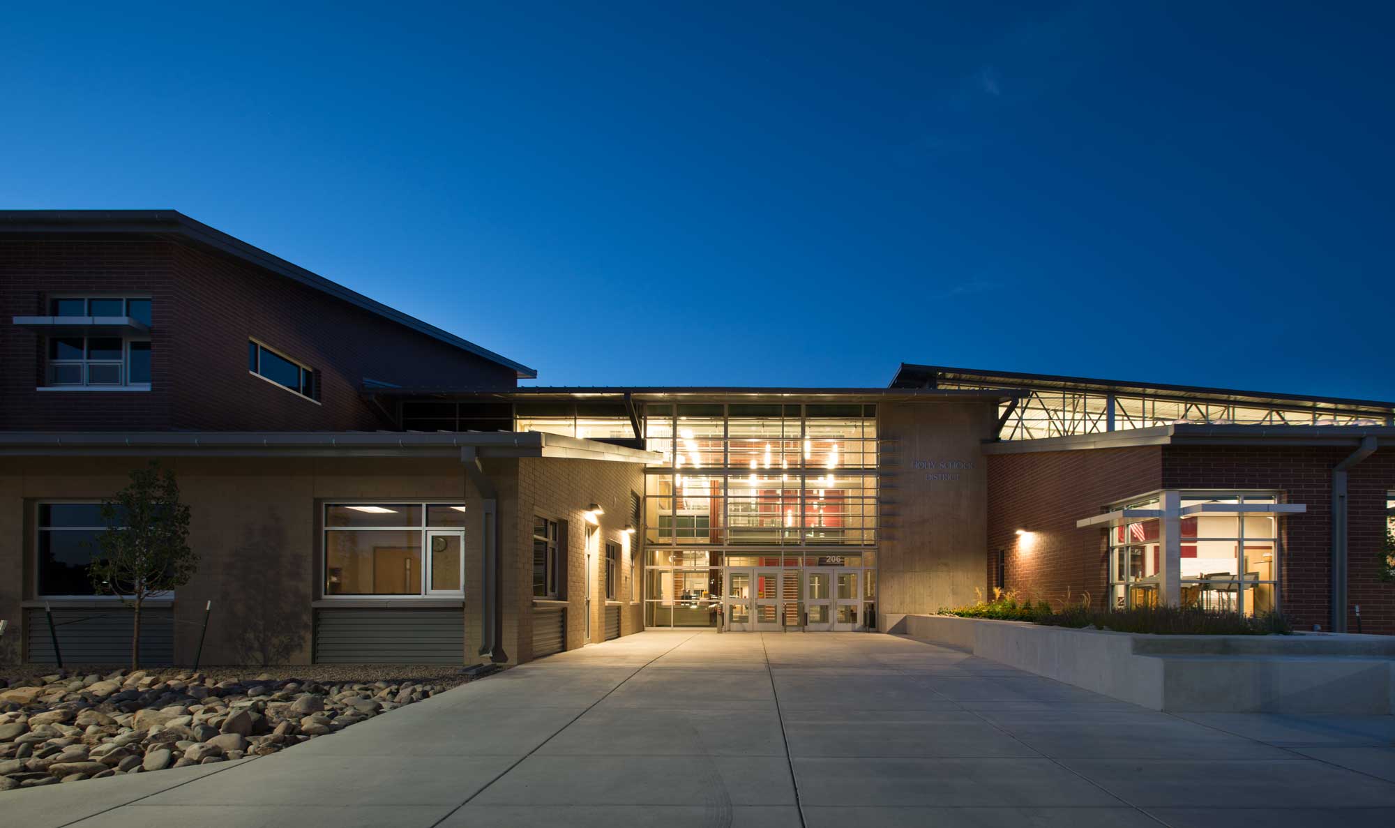 Nighttime exterior view of Holly PK-12 with light from the interior illuminating the entryway. 