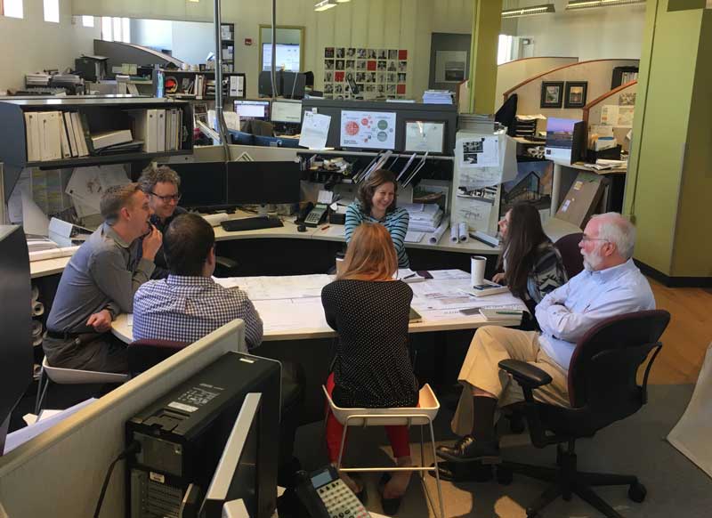 Four men and three women sitting around a conference table having a discussion.