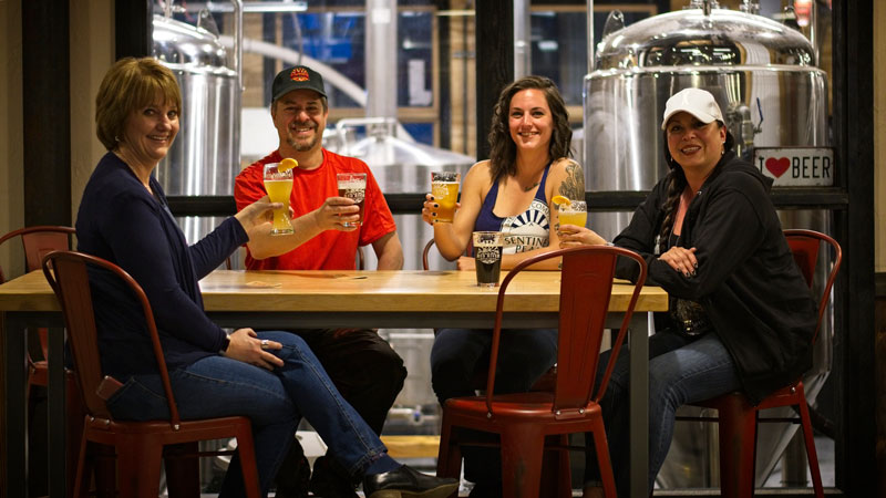 Four people raising their beer glasses in a toast. 