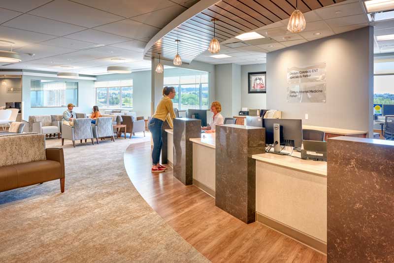 Interior view of the Peak Medical Office Building's third-floor waiting area, featuring a modern design with comfortable seating, large windows allowing natural light, and a calming color palette. A few people are present, contributing to the welcoming and functional atmosphere.