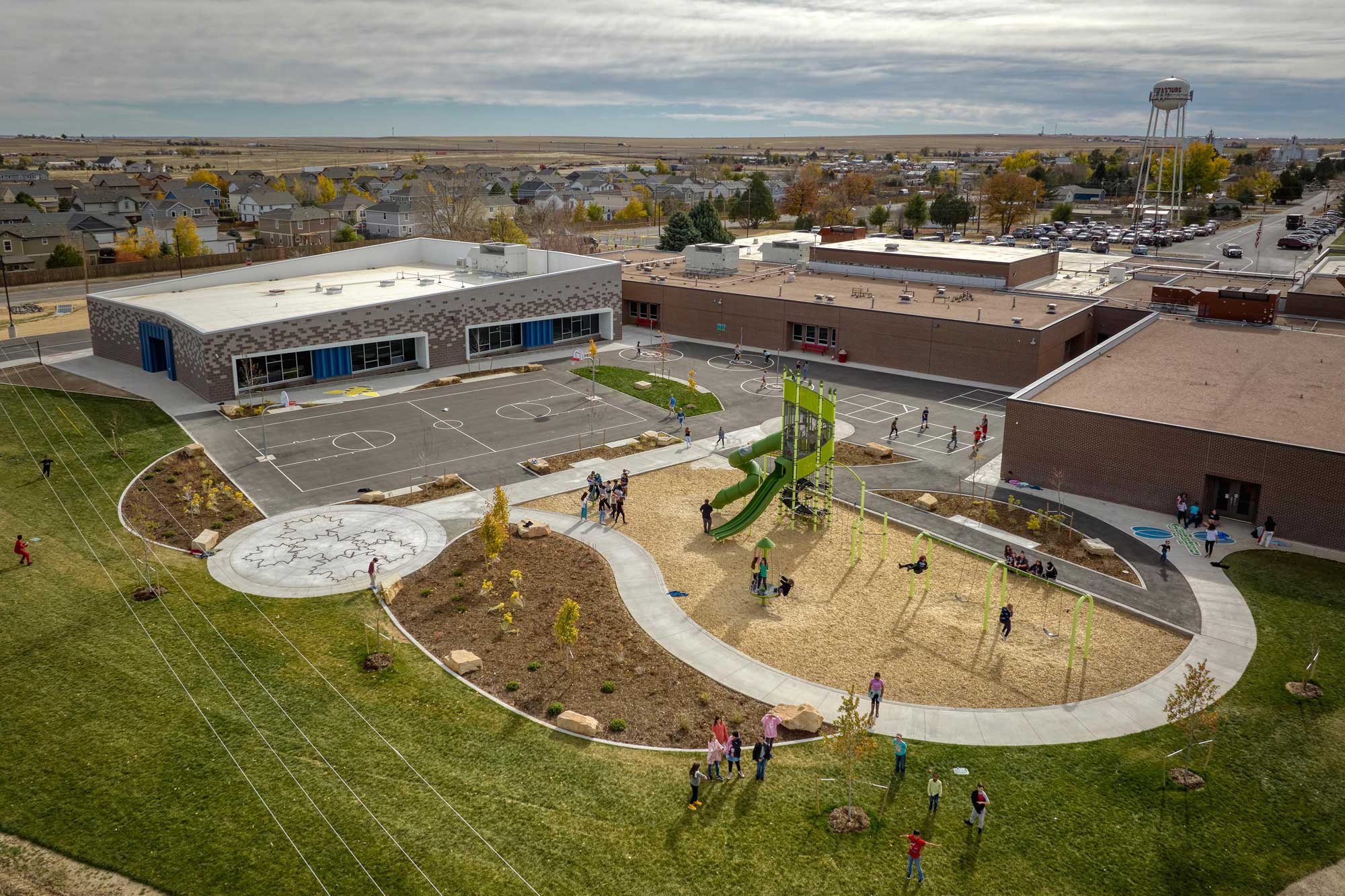 Exterior view of Strasburg Elementary School, showcasing a modern design with a combination of brick and metal materials. The building features large windows and a welcoming entrance, complemented by a well-maintained landscape under a clear sky.