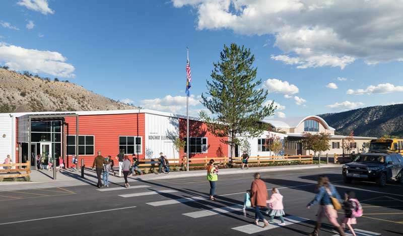 Exterior view of Ridgway Elementary School, featuring a modern design with wood and metal accents, large windows, and a welcoming entrance. The surrounding landscape complements the school's natural setting, creating an inviting learning environment.