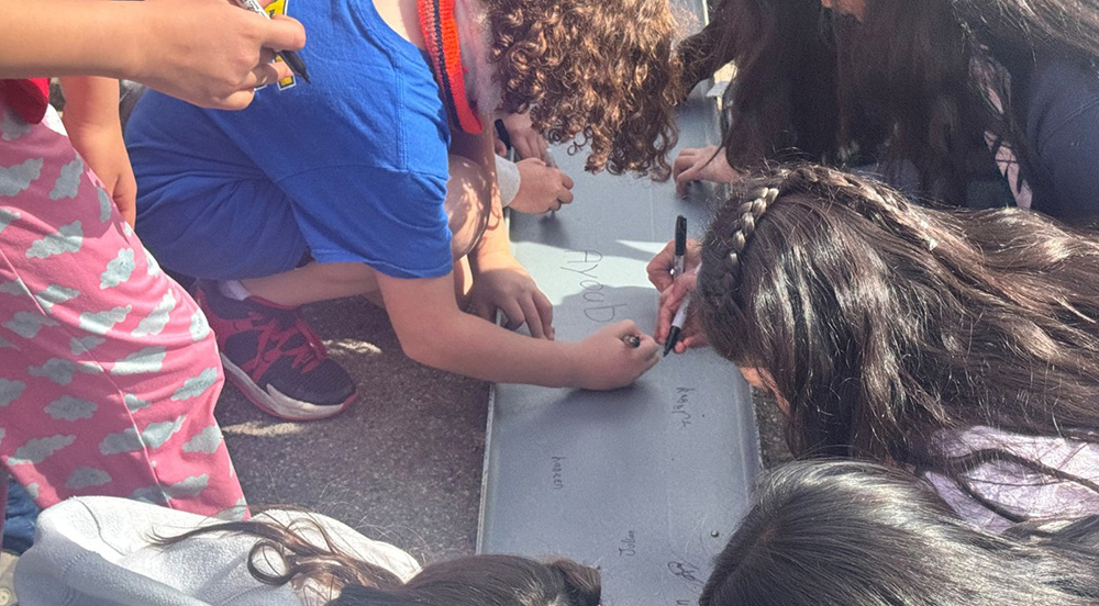 students sign a beam for the new holly hills elementary